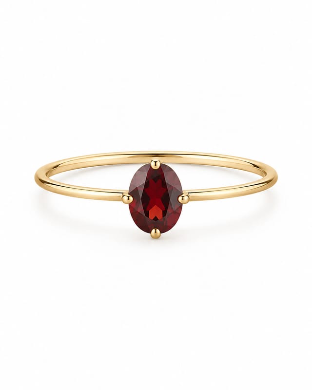 Fine gold-tone band with a claw-set deep red oval January garnet-coloured stone