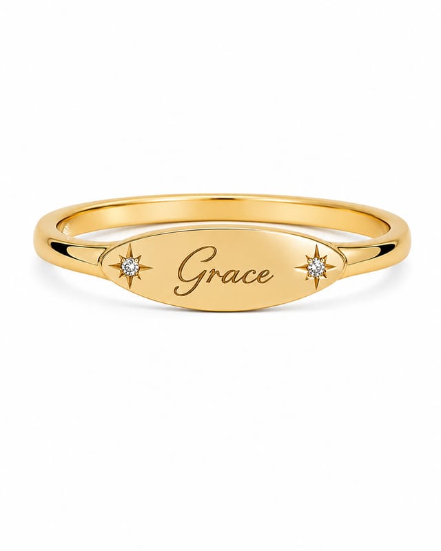 Gold-tone oval signet ring engraved “Grace”, with a small star-set stone on each side of the plate