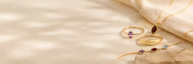 Engraved rings, a pendant and a bracelet laid out on cream linen.